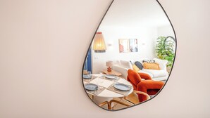 Una sala de estar moderna con comedor, paredes blancas y un espejo grande.