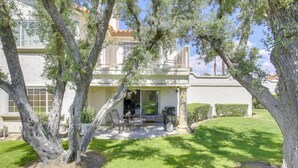 Une maison avec un patio, du mobilier d’extérieur et une pelouse.