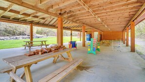 A covered picnic area with wooden benches, picnic tables, and a playground with colorful equipment.