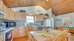 A kitchen with wooden cabinets, a microwave, stove, and a dining table with chairs.