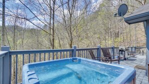 A hot tub on a wooden deck with a view of trees.