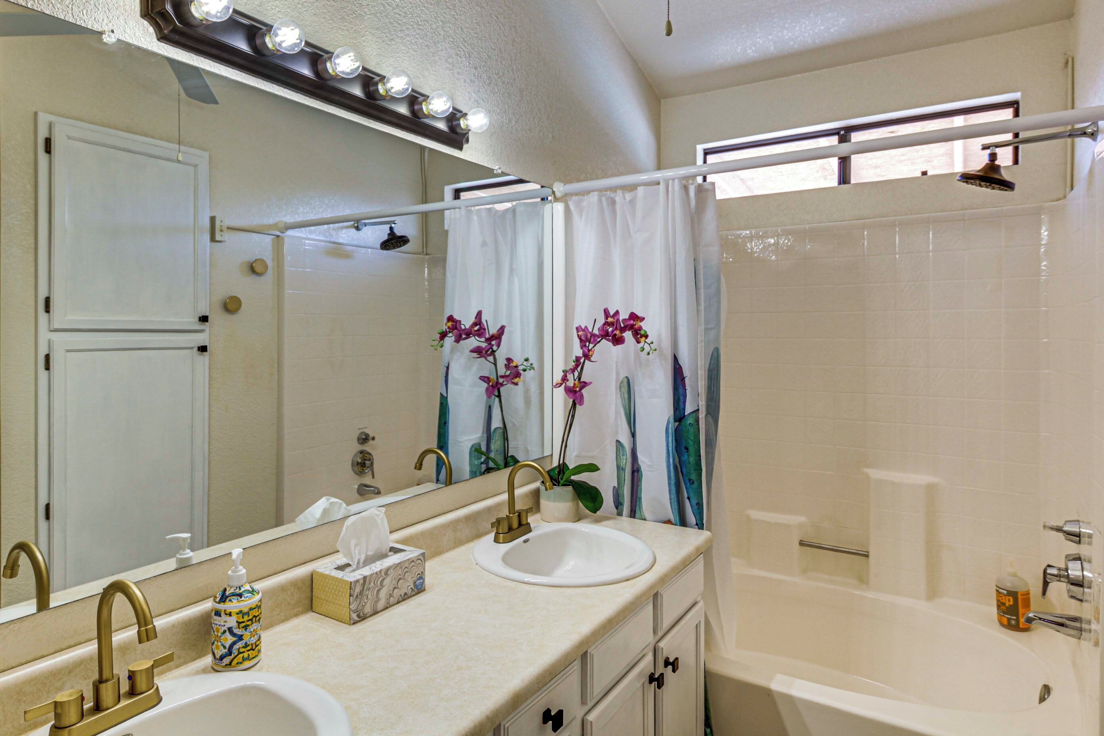 A bathroom with two sinks, a large mirror, and a shower area.