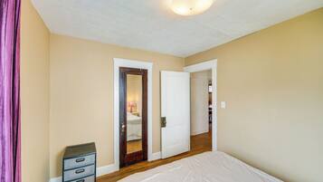 Un dormitorio con una cama, un aparador y dos puertas que dan a otras habitaciones.