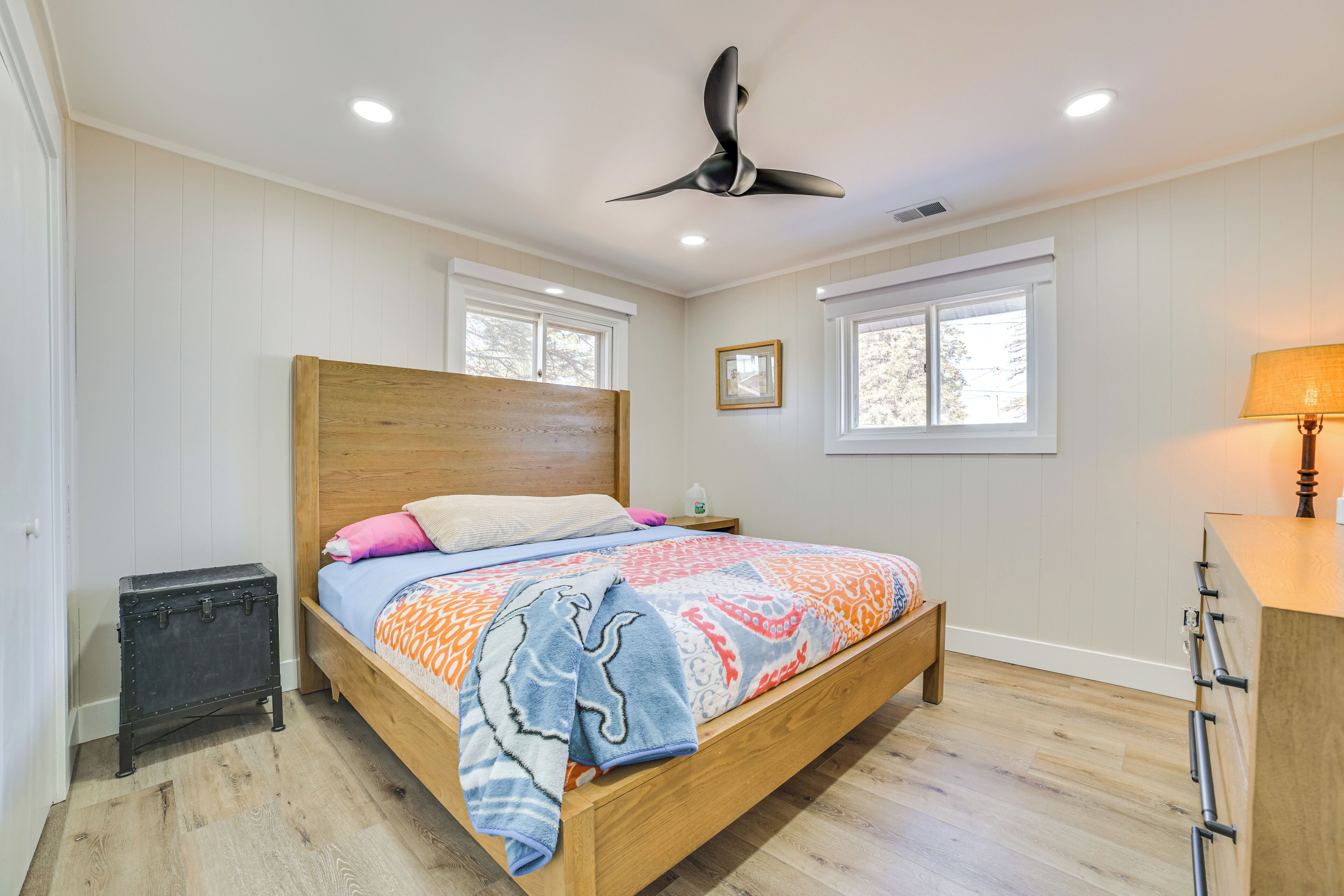 A bedroom with a wooden bed, a ceiling fan, and a nightstand with a lamp.