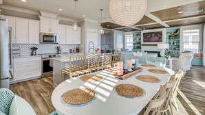 A modern kitchen with white cabinets, stainless steel appliances, and a large island with woven placemats.