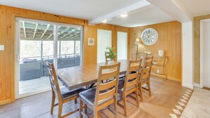 A dining area with a wooden table and chairs, a clock on the wall, and a sliding glass door leading to an outdoor patio.
