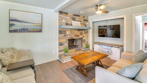 A living room with a stone fireplace, a wooden coffee table, and a sofa.