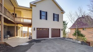 Ein zweistöckiges Haus mit überdachter Veranda, Garage und Auffahrt.