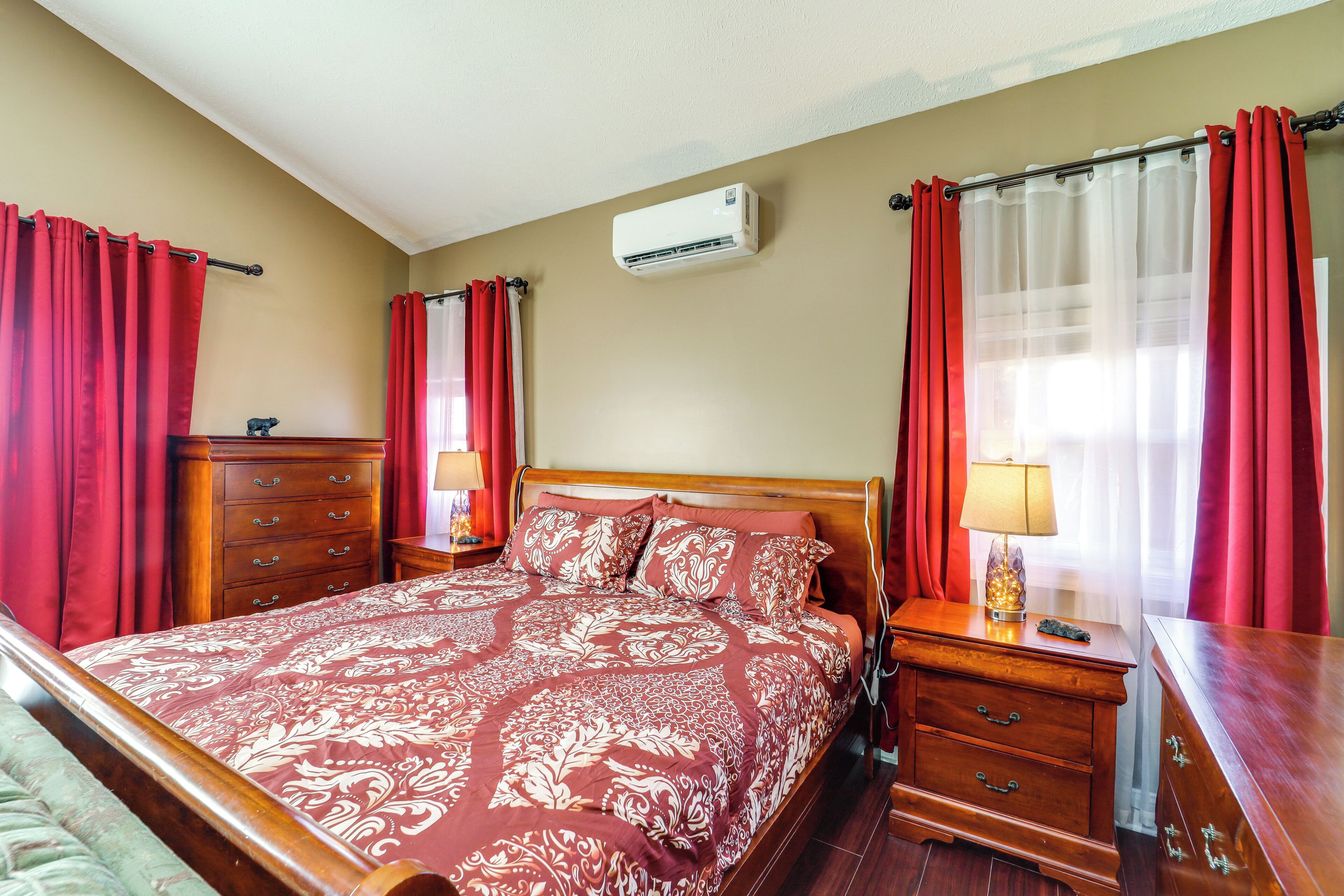 A neatly made bed with a patterned bedspread, a wooden nightstand with a lamp, and a dresser with a mirror.