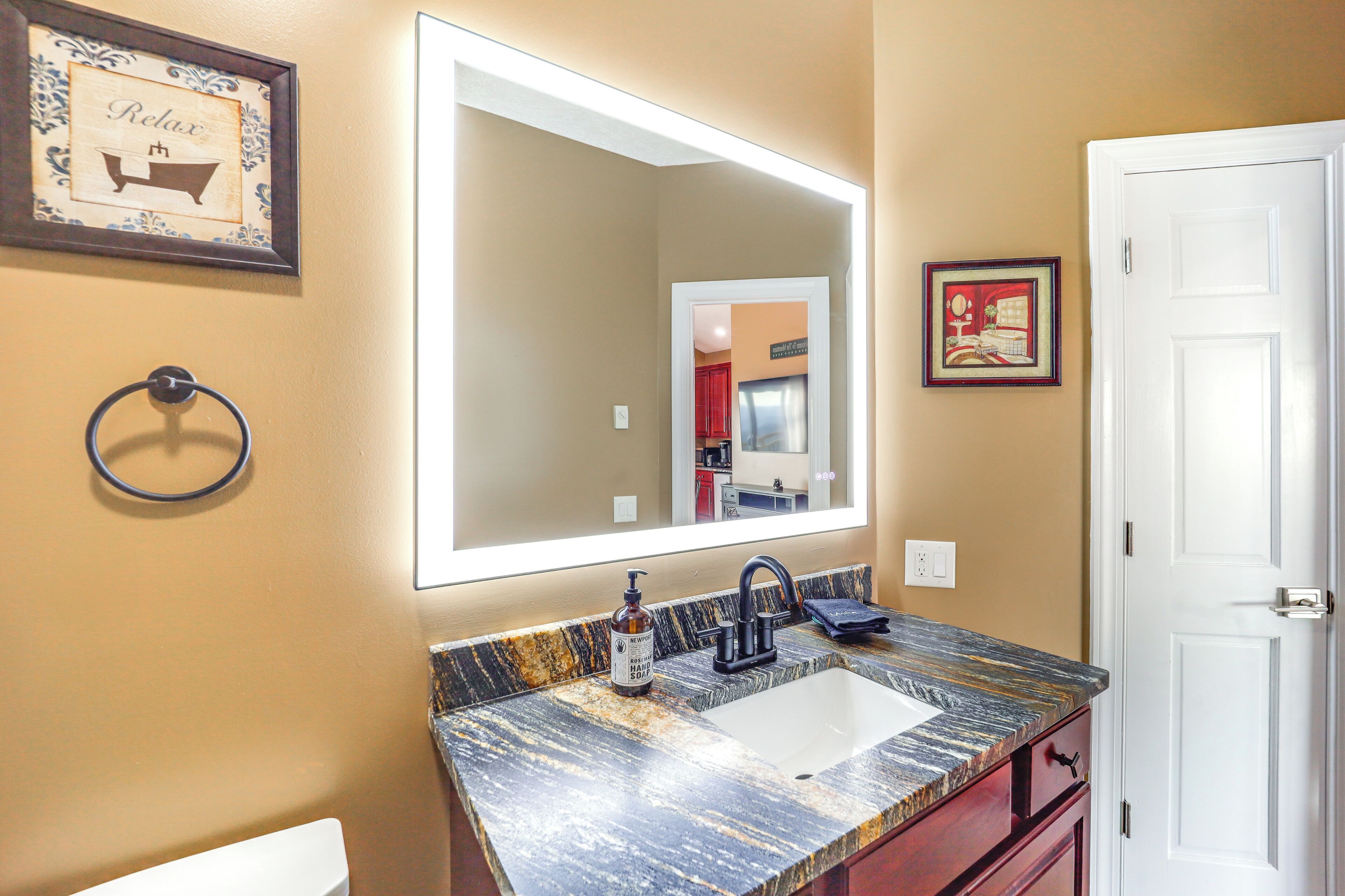 Une salle de bain avec un grand miroir, un lavabo et une porte.