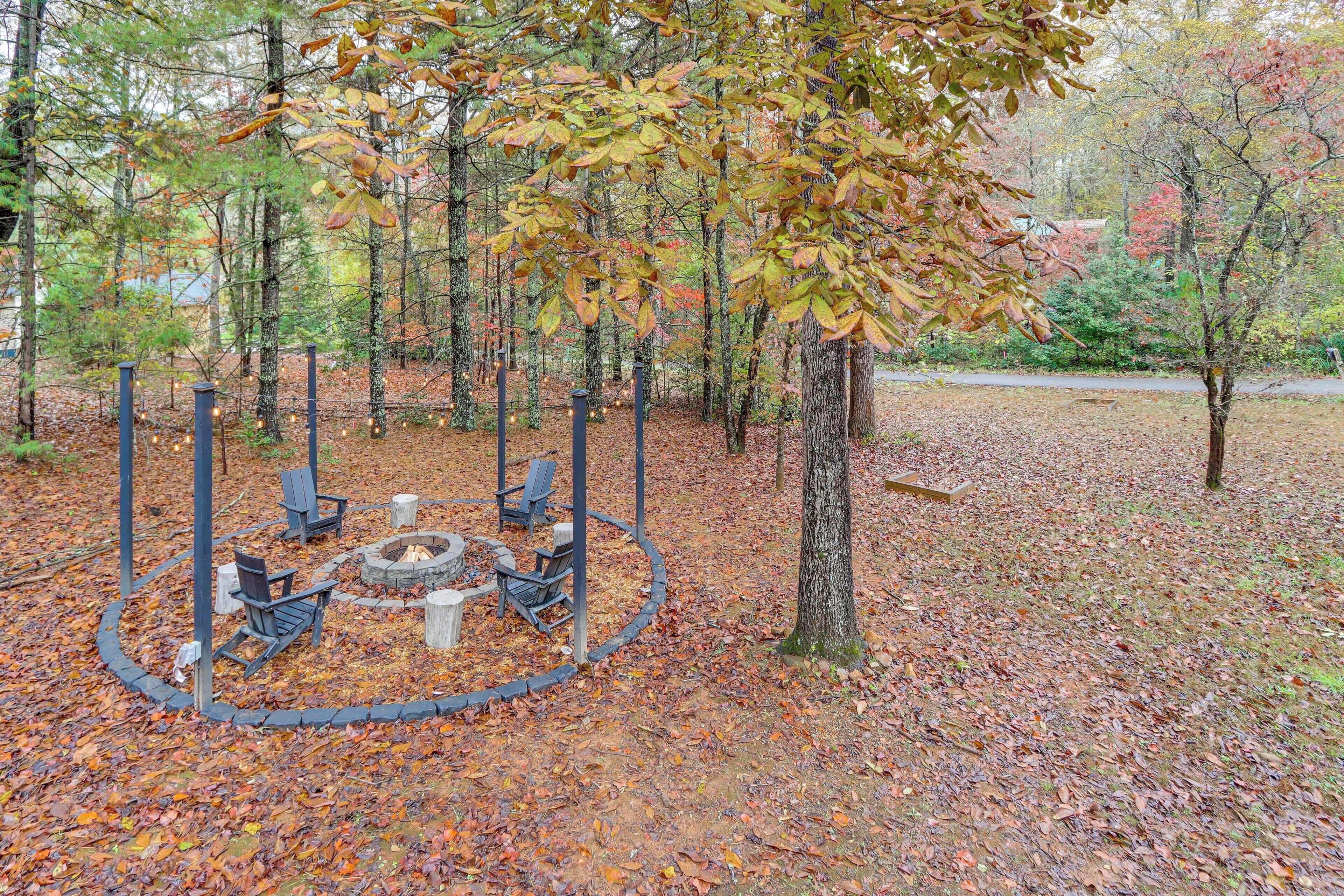 A circular seating area with benches and a fire pit surrounded by trees in a park.