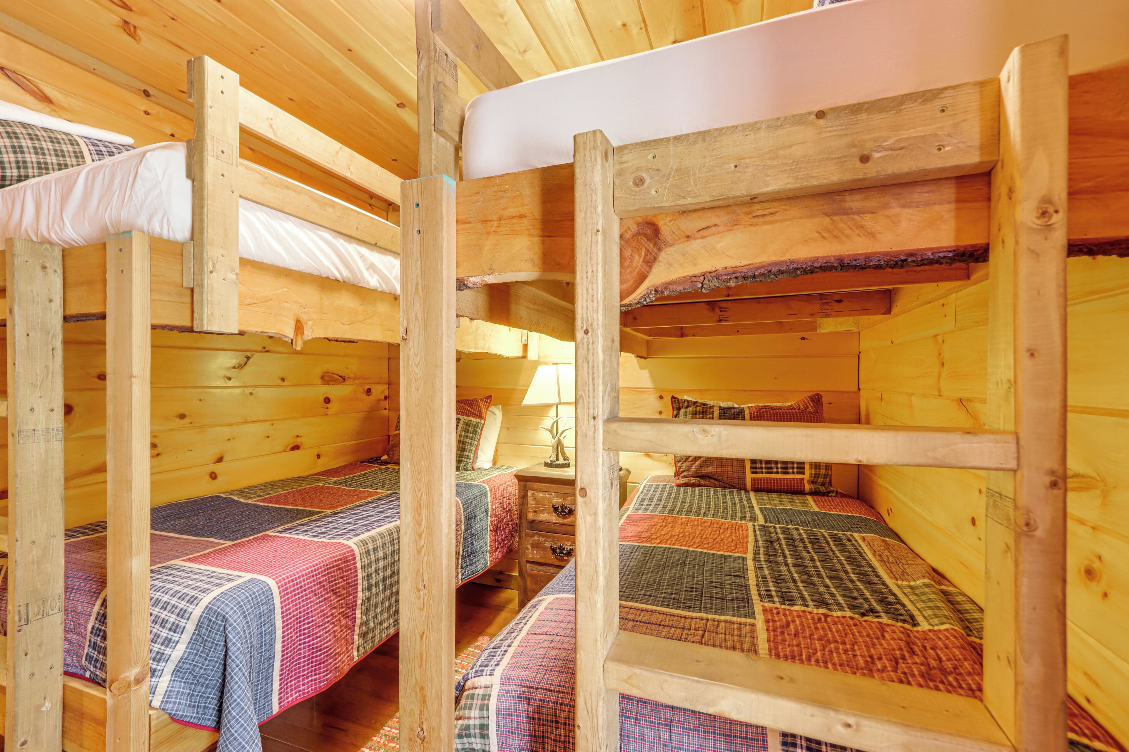 A cabin with bunk beds, wooden walls, and a small bedside table with a lamp.