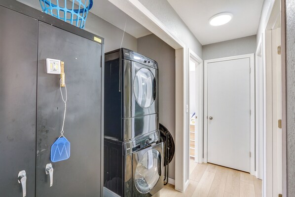A laundry room with stacked washers and dryers, a blue laundry basket, and a door leading to another room. - 3 Mi to the Lake: Rocky Mount Home w/ Water Views! (Rocky Mount)