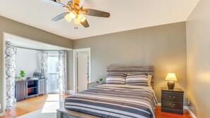 A bedroom with a bed, a nightstand, a ceiling fan, and a view to a balcony.