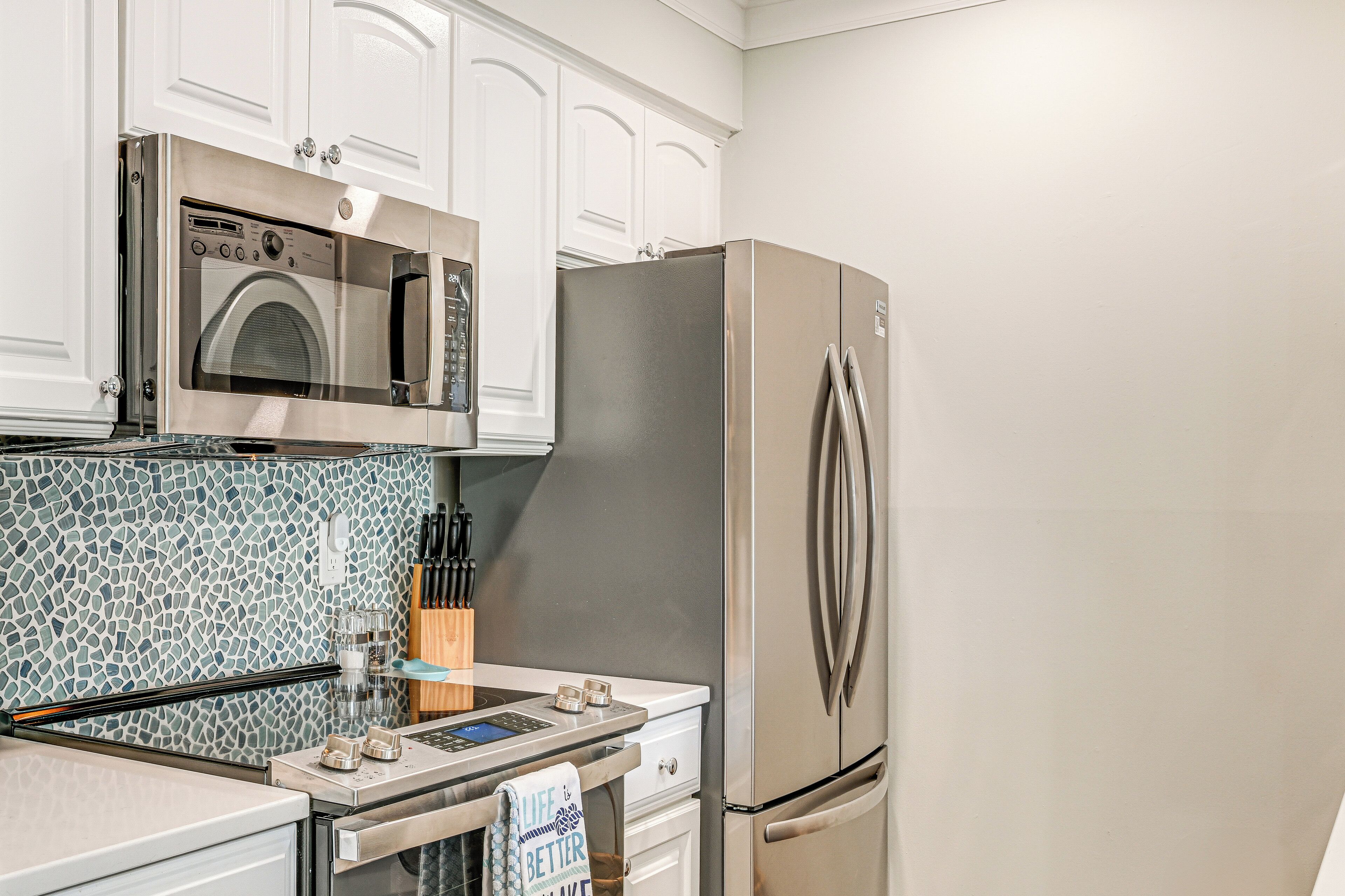 A kitchen with a built-in oven, microwave, and stainless steel refrigerator.