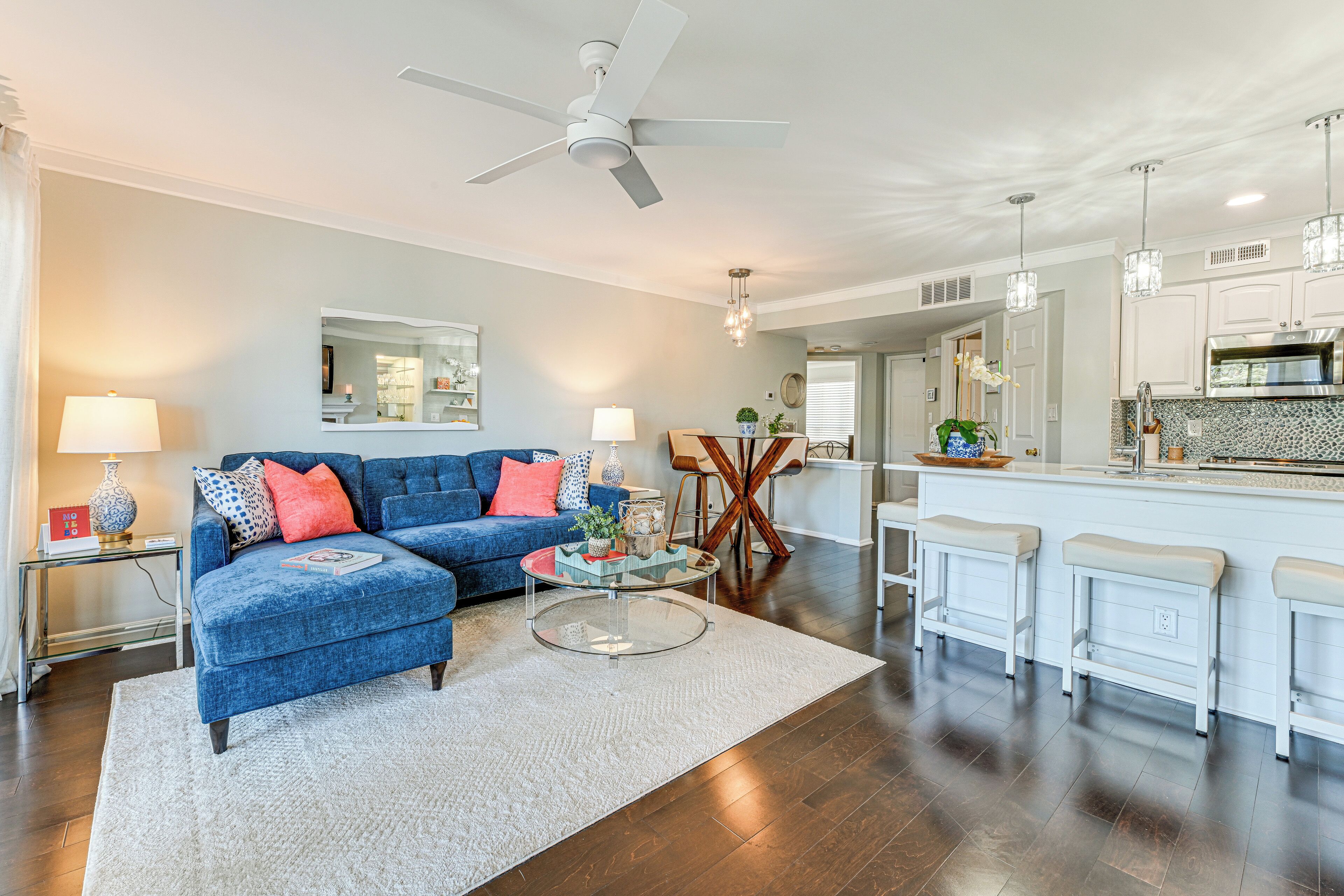 A modern living room with a blue sofa, a round coffee table, and a dining area with a wooden chair and a small table.