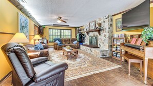 A spacious living room with a fireplace, leather chairs, a coffee table, and a bookshelf. - Lake Access + Private Patio: Sunny Inverness Apt! (Inverness)