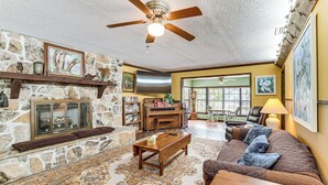 A living room with a stone fireplace, a ceiling fan, a piano, and a couch. - Lake Access + Private Patio: Sunny Inverness Apt! (Inverness)