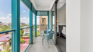 Un balcon avec vue sur la ville, un coin repas avec des chaises et un lit.