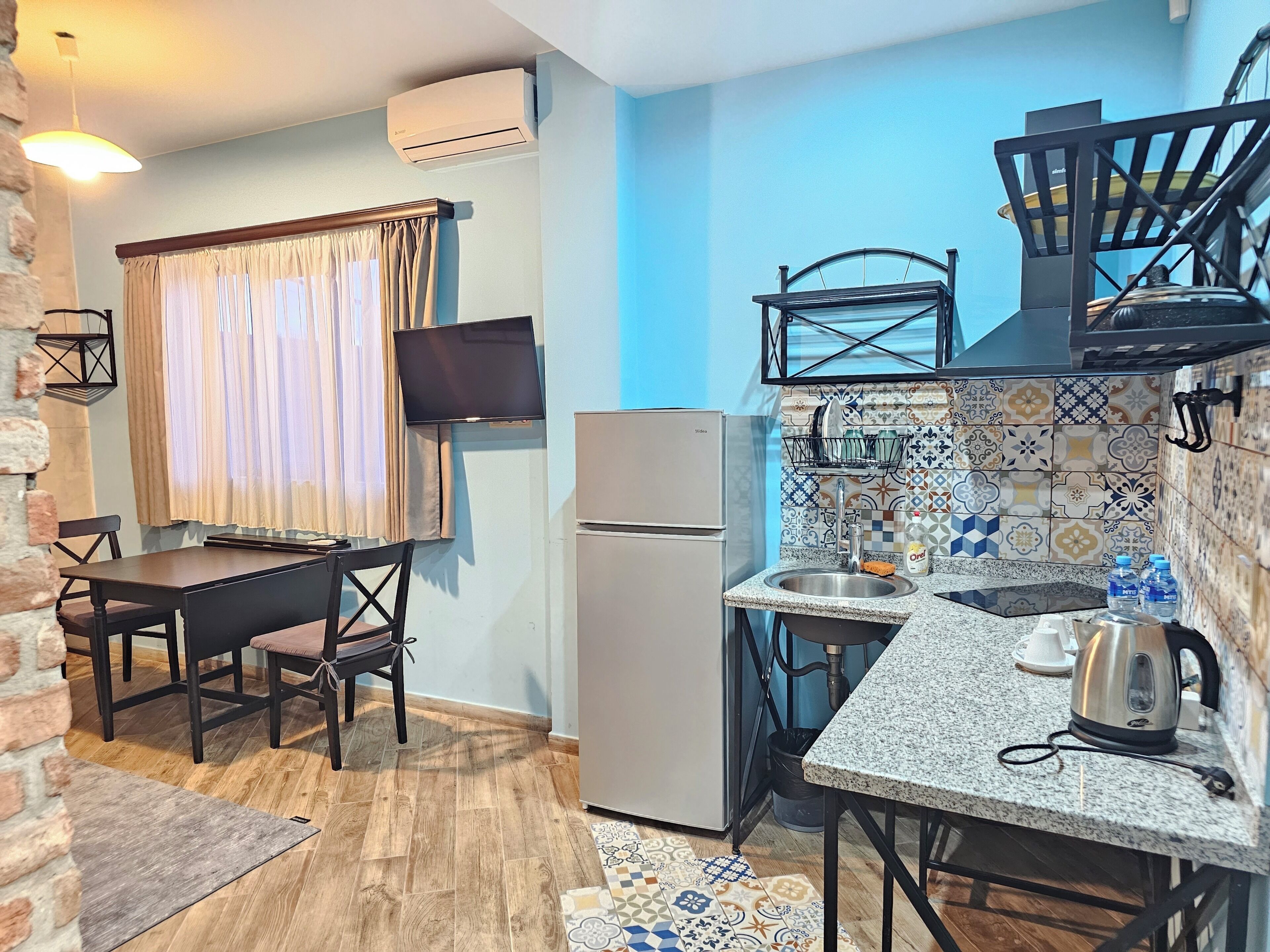 A compact kitchen with a refrigerator, a sink, and a dining area with a table and chairs.