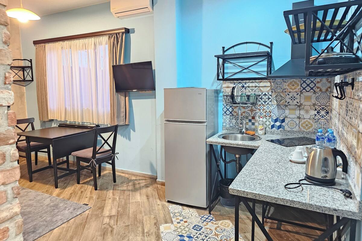 A compact kitchen with a refrigerator, a sink, and a dining area with a table and chairs.