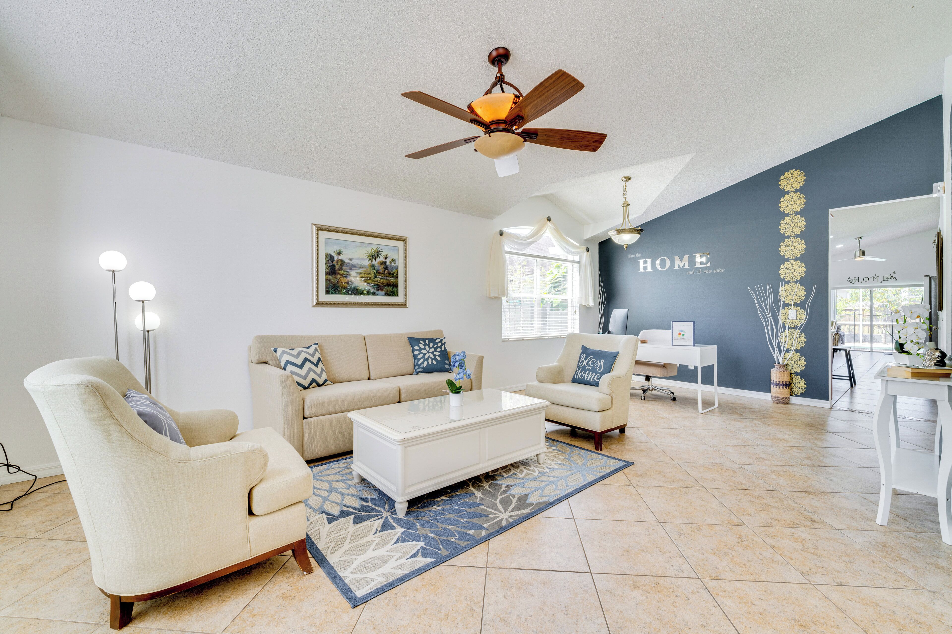 A living room with a beige sofa, a white coffee table, and a ceiling fan.