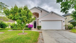 A residential house with a garage, a well-maintained lawn, and a tree in the front yard. - 12 Mi to Disney: Family Home w/ Lanai in Davenport (Davenport)
