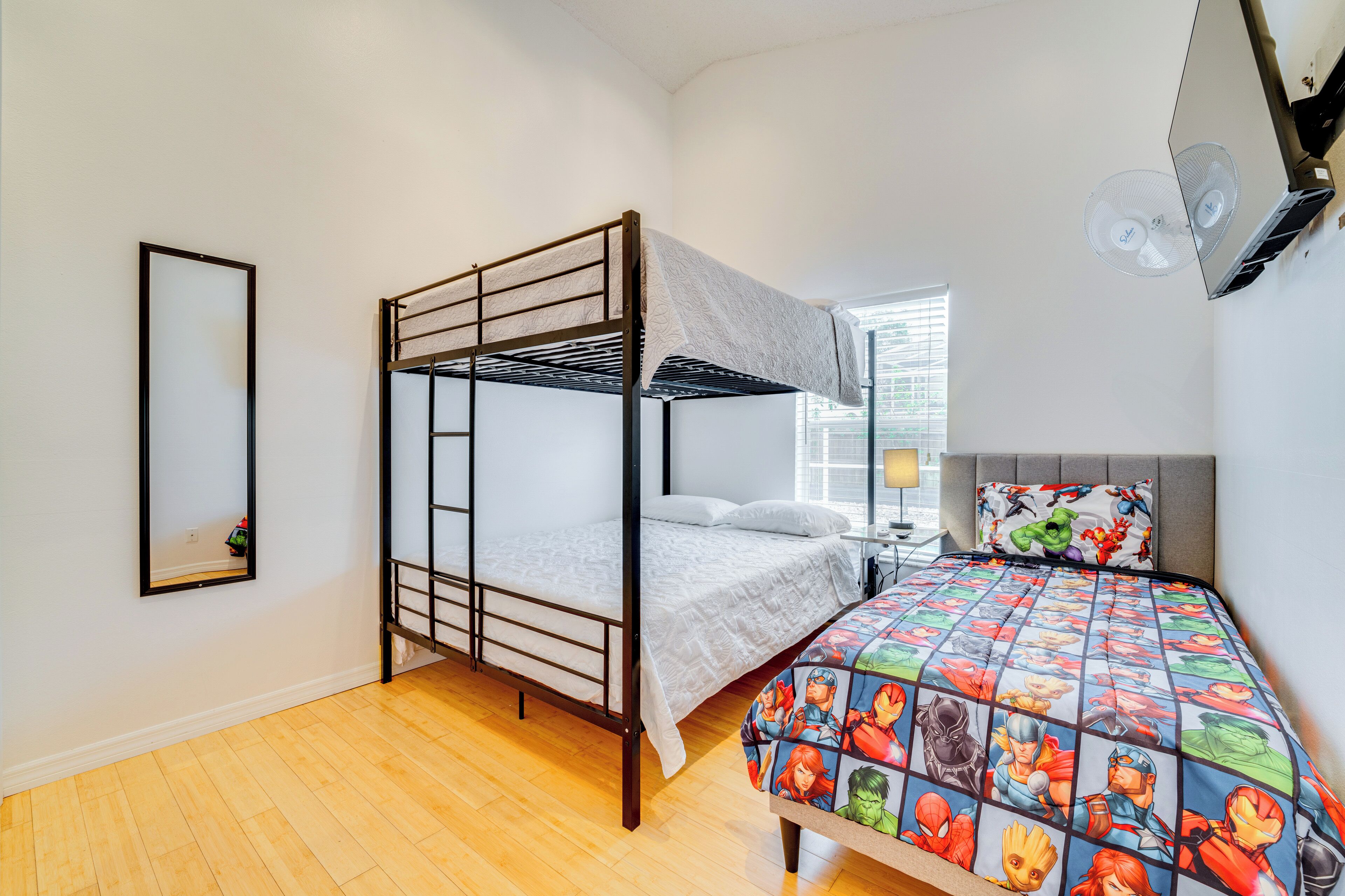 Un lit superposé avec un matelas blanc et une couette aux couleurs vives, ornée de motifs de super-héros.