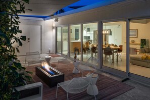 Un espace de vie moderne doté d’un foyer, de sièges et d’une porte vitrée donnant sur une salle à manger.