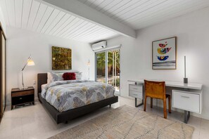 Une chambre à coucher moderne, avec un lit, un bureau, une chaise et des œuvres d’art.