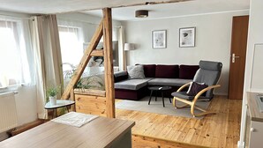 Un salon moderne avec un plancher en bois, un canapé d’angle, un fauteuil à bascule et une petite table.