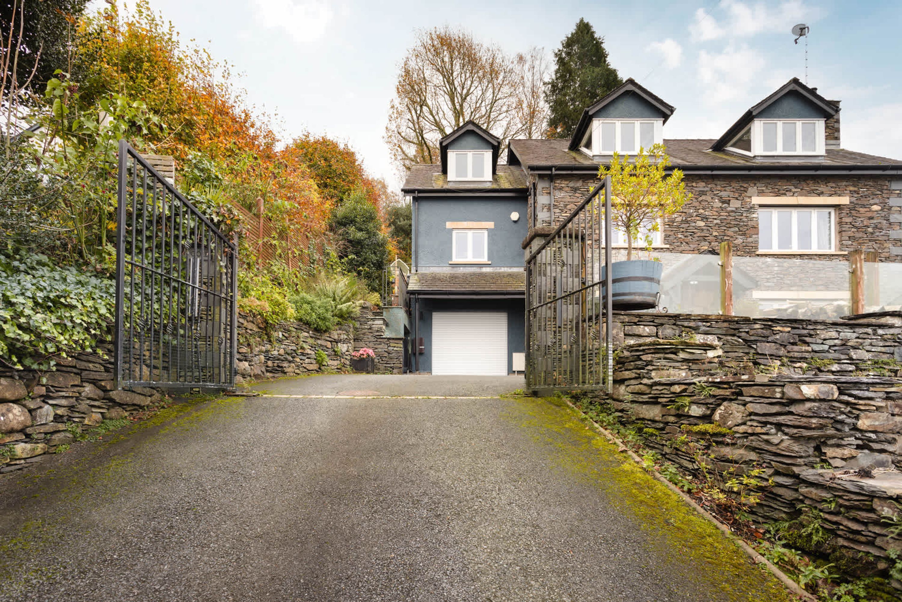 Ein zweigeschossiges Haus mit einer Stein-Fassade, einer Garage und einem ehrkundeten Auffahrt.