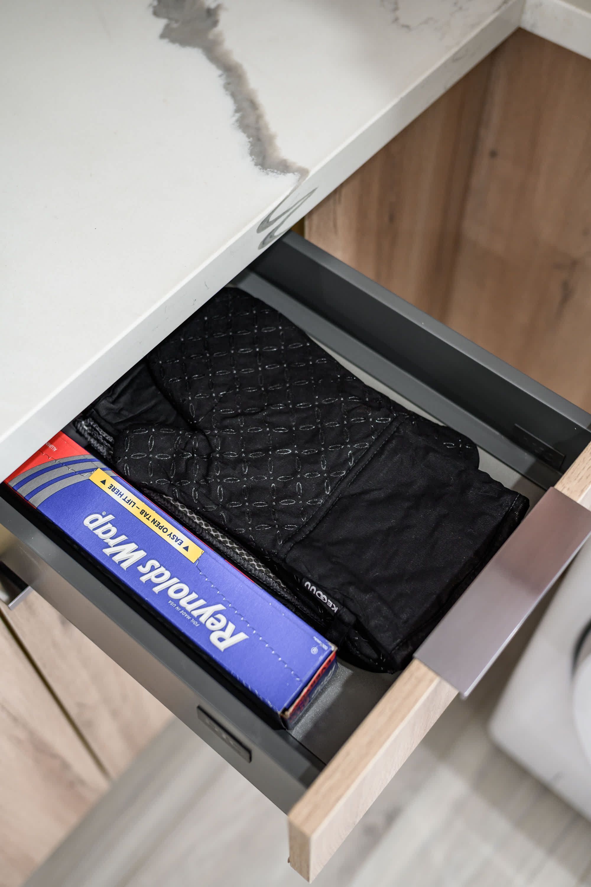 A drawer with a black quilted bag and a box labeled "Reyko's World."