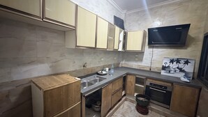 A compact kitchen with wooden cabinets, a built-in dishwasher, and a marble backsplash. - Haysym (Dakar)