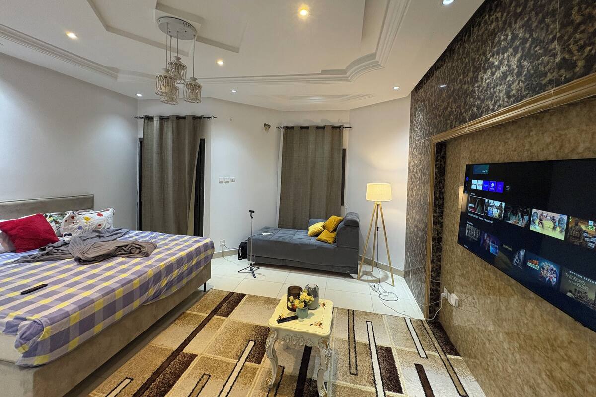 Une chambre d’hôtel moderne équipée d’un lit, d’un canapé, d’un téléviseur fixé au mur et d’un ventilateur de plafond.