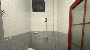 A small, narrow bathroom with a toilet, bidet, and shower. - Haysym (Dakar)