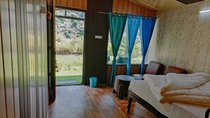 Ein Schlafzimmer mit Bett, einem kleinen Tisch und Blick auf einen Garten durch eine Schiebetür.