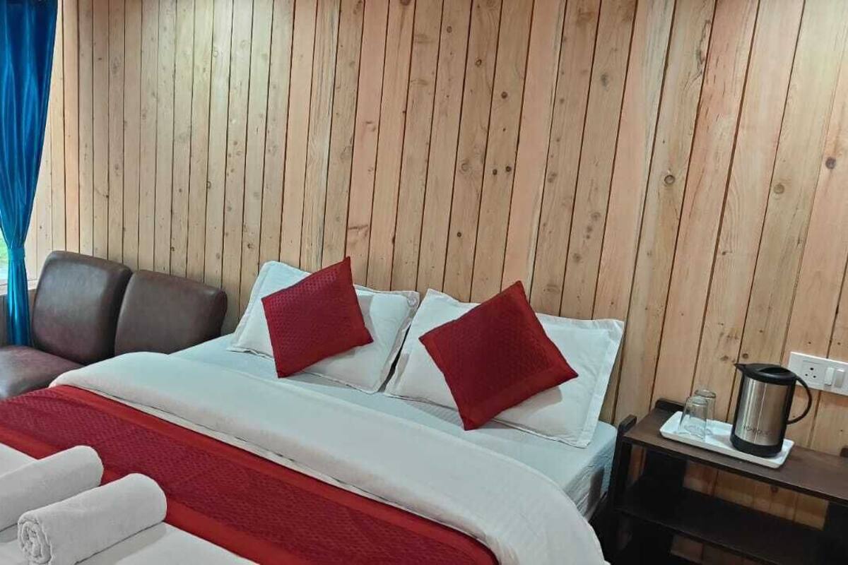 Um quarto com painéis de madeira, uma cama, uma cadeira, uma mesa de cabeceira e uma janela com cortinas.