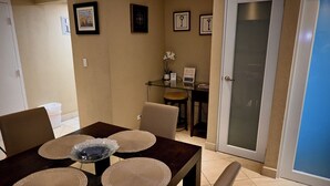 A dining area with a table set for four, a glass cabinet, and framed pictures on the wall. - Privilege Apartment @ San Juan Convention Center with A/C, parking and Wi-Fi (San Juan)