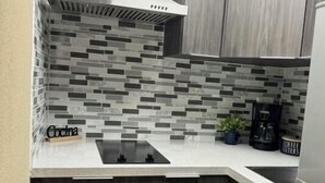 A modern kitchen with a white countertop, dark wood cabinets, and a tiled backsplash. - Privilege Apartment @ San Juan Convention Center with A/C, parking and Wi-Fi (San Juan)