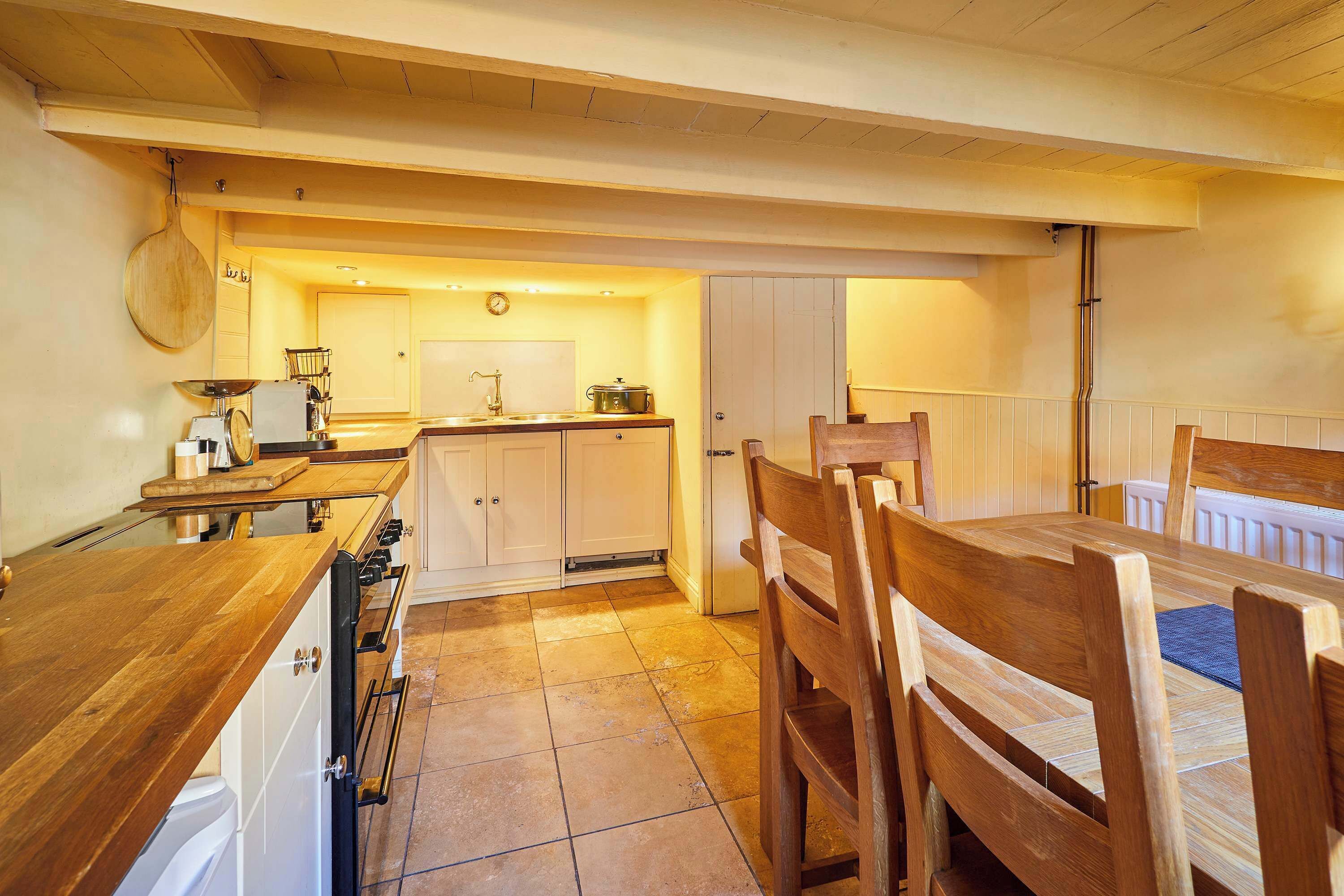 A kitchen with wooden cabinets, a sink, and a dining area with wooden chairs and a table.