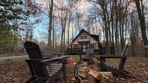 Una cabaña con terraza, pozo de fuego y sillas Adirondack.