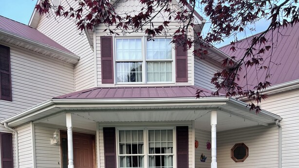 A two-story house with a porch, steps, and potted plants. - Large spacious house with ample parking for large groups. (Delbarton)