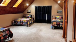 A bedroom with two beds, wooden ceiling, skylights, and a door. - Large spacious house with ample parking for large groups. (Delbarton)