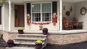 A house with a porch decorated for Halloween, featuring scarecrow figures and pumpkins. - Large spacious house with ample parking for large groups. (Delbarton)