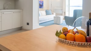 Een moderne keuken met witte kasten en een houten aanrecht. Op het aanrecht staat een fruitschaal met sinaasappels, bananen en appels.