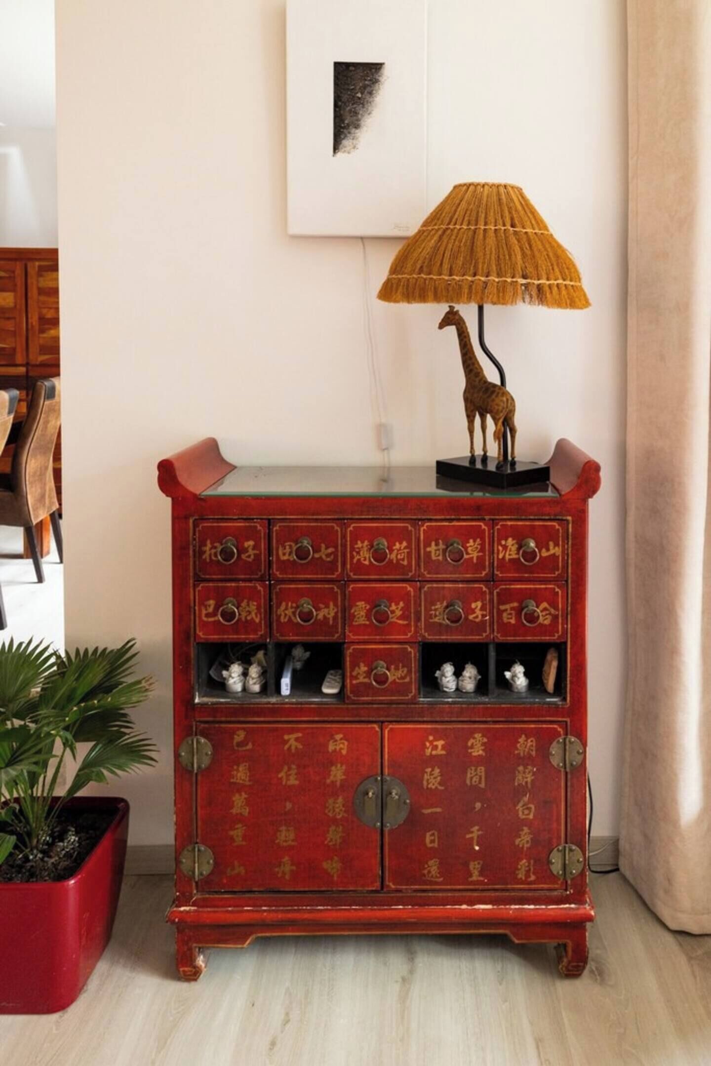 Un mueble rojo con varios cajones y una figurita de jirafa encima.