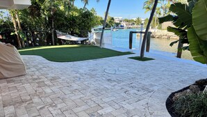 A paved patio area with a hammock, a small pool, and tropical vegetation.