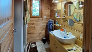 Baño de cabaña de madera con lavabo, espejo y toallero.