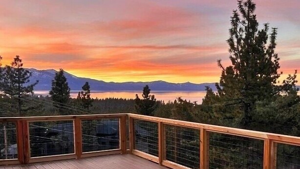 A wooden deck with a hot tub, overlooking a lake and mountains during sunset. - Hch1083 - Mountain Serenity 4 Bedroom Home (South Lake Tahoe)
